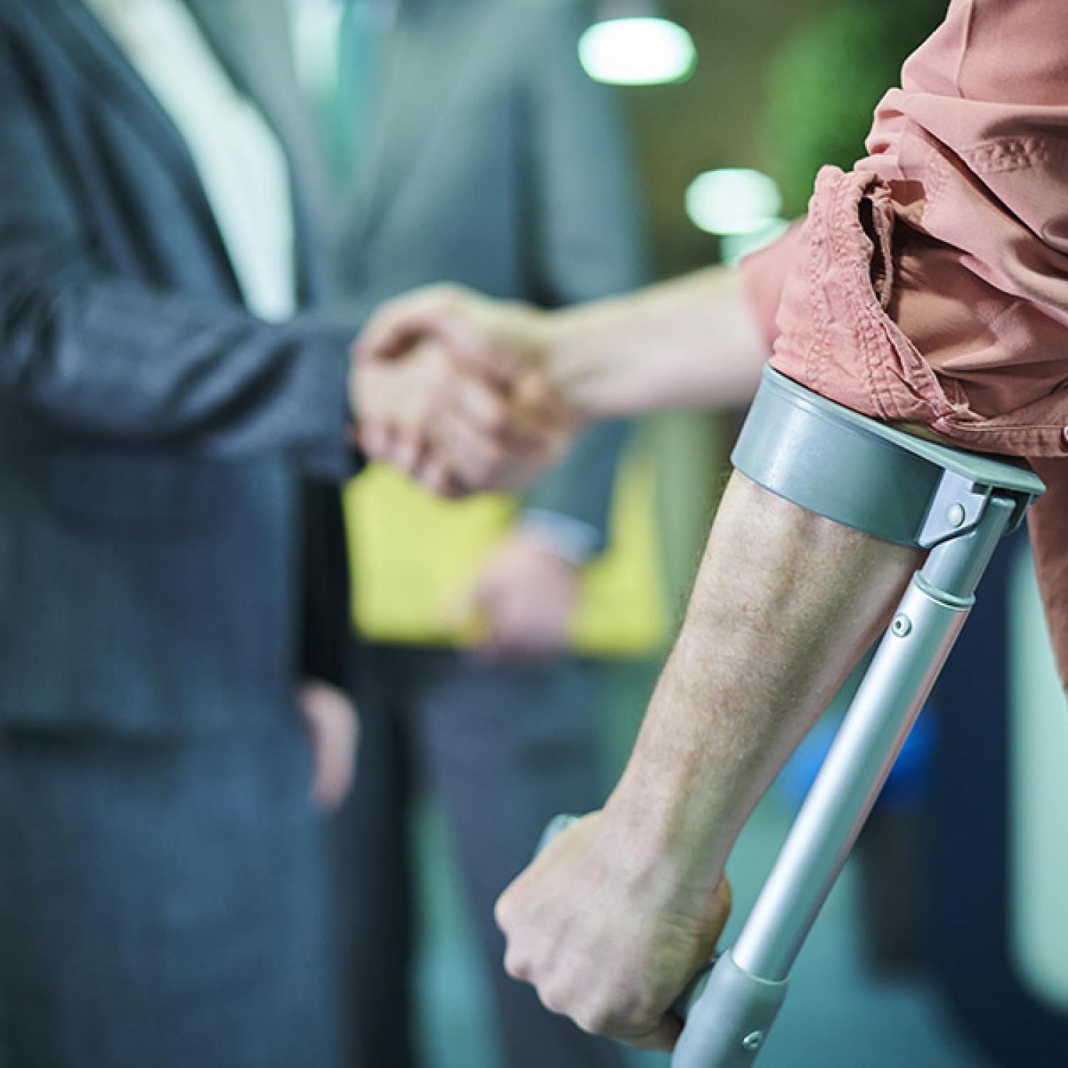 Person using a crutch, shaking hands with someone