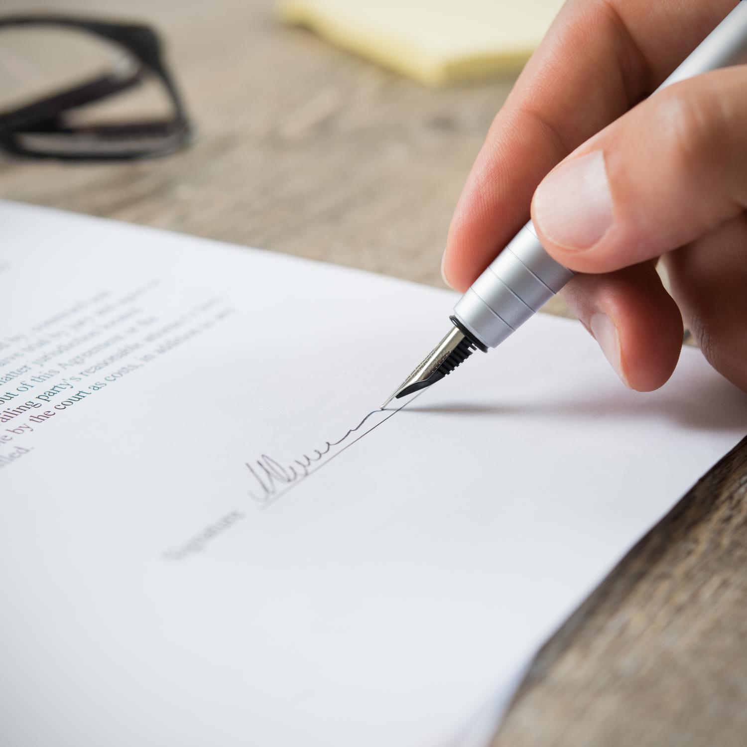 Person signing a document with a fountain pen