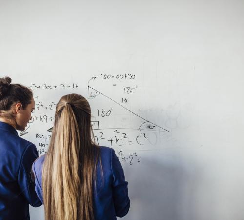 Two schoolgirls do maths on a whiteboard