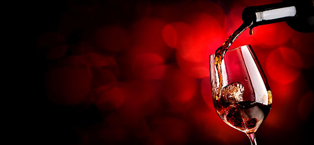Wine pouring in wineglass on the vinous background