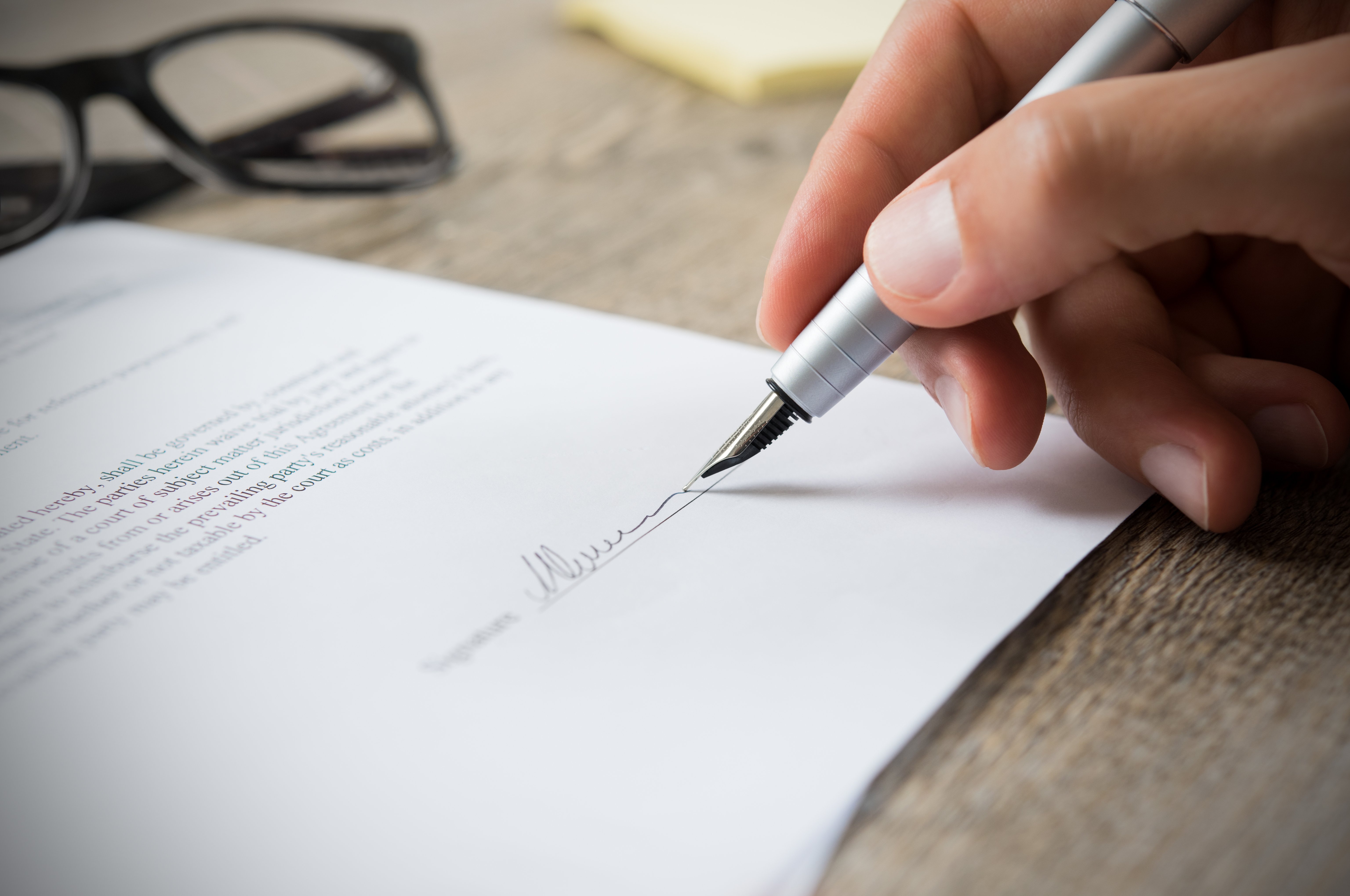 Person signing a document with a fountain pen