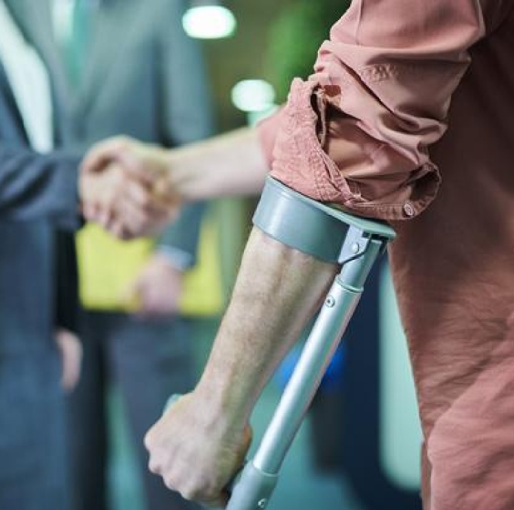 A person using a crutch shaking the hand of someone