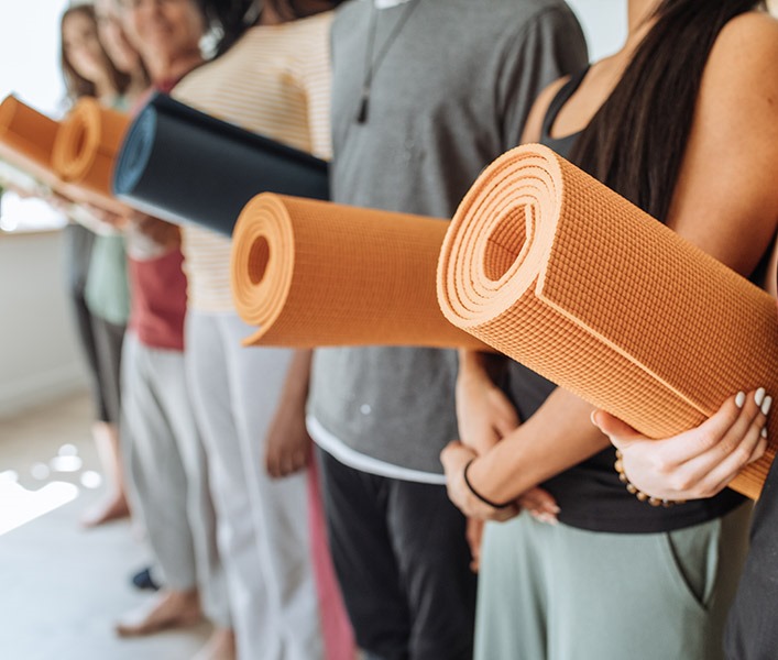 A group of people holding their yoga mats in the studio
