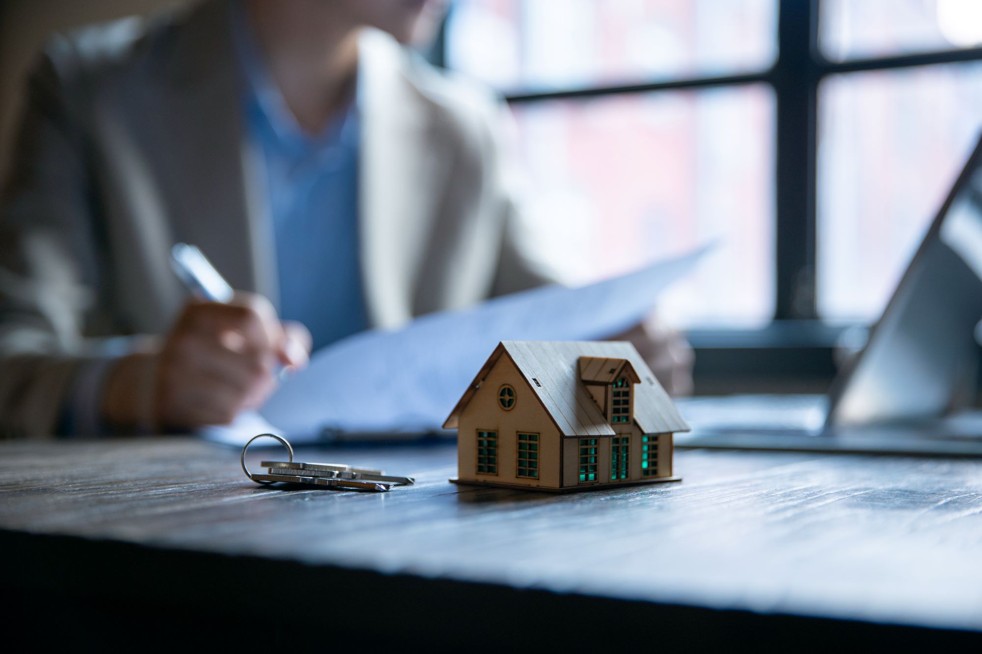 A person signing contract papers to purchase a house