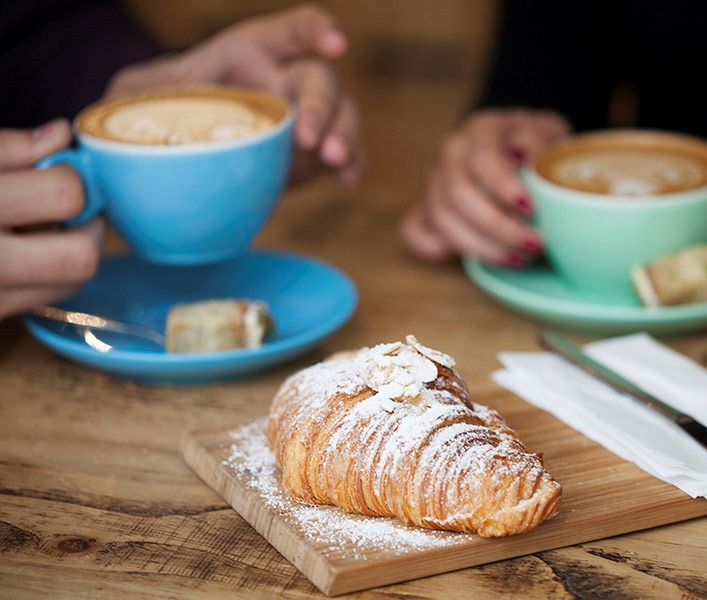 Two people at a cafe having coffee and a croissant