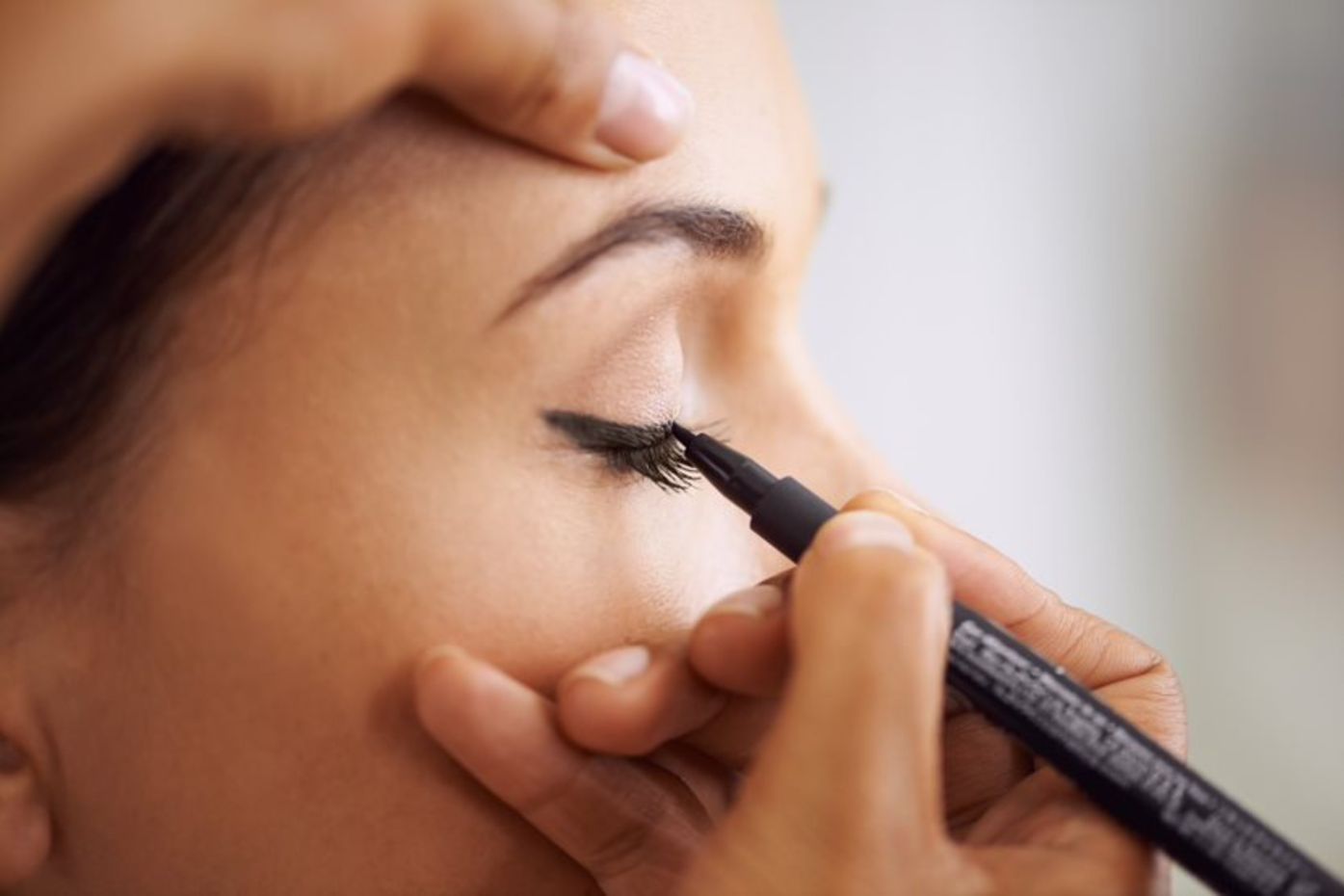 beauty therapist applying eyeliner for client