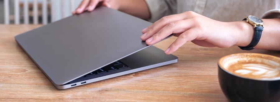 image showing professional opening laptop in cafe with cappuccino on table