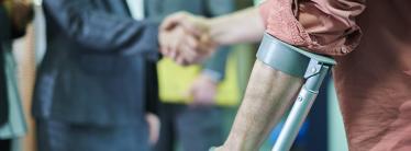 Person using a crutch, shaking hands with someone