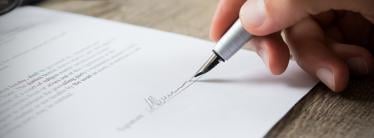 Person signing a document with a fountain pen