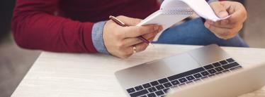 A man makes notes at his laptop