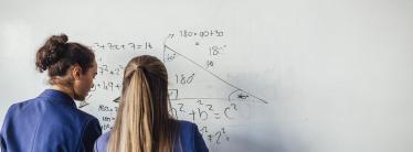 Two schoolgirls do maths on a whiteboard