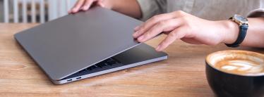 image showing professional opening laptop in cafe with cappuccino on table