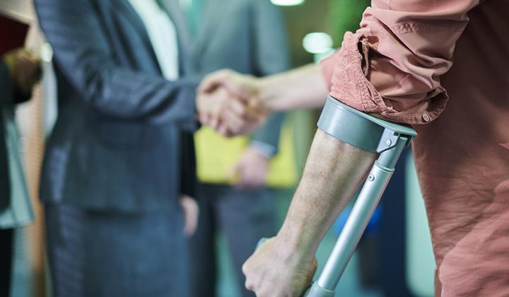 Person using a crutch, shaking hands with someone