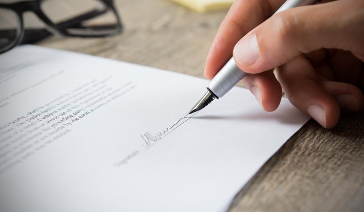 Person signing a document with a fountain pen