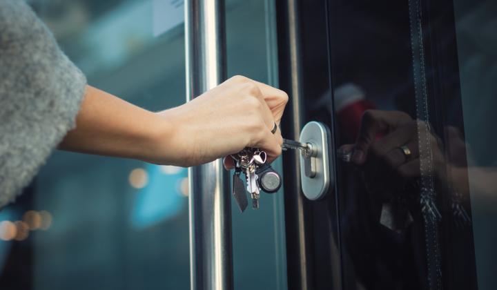 business owner using a key to open front door