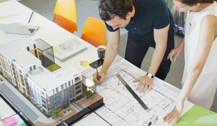 Two architects looking at plans and a model for an office building