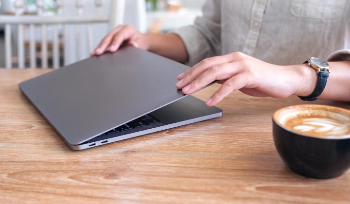 image showing professional opening laptop in cafe with cappuccino on table