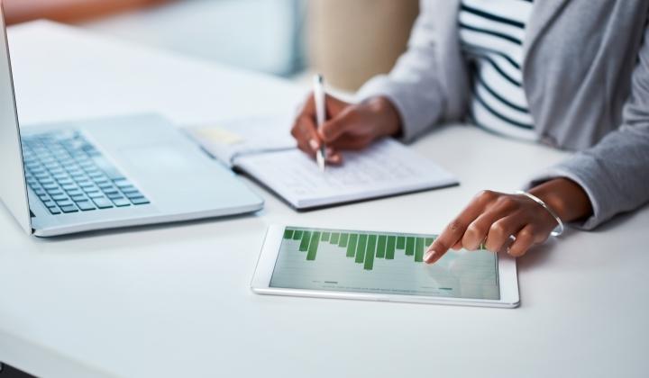 woman on laptop with ipad looking at marketing chart