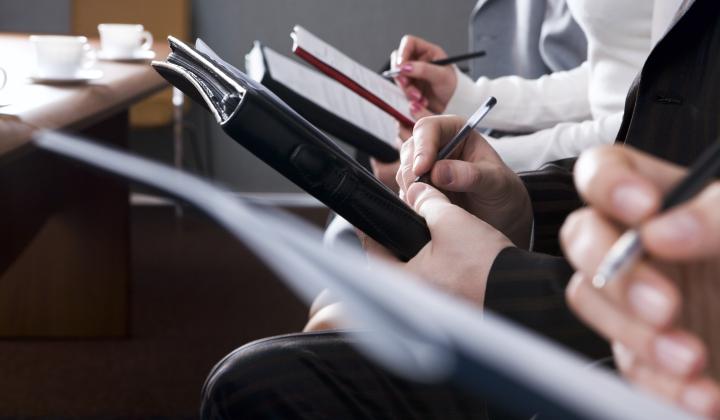 a group of people sat with clipboards and books making notes