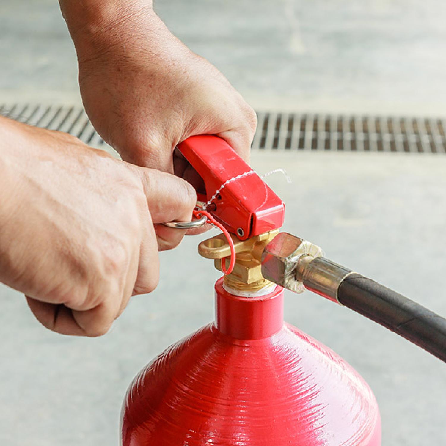 A person pulling out the pin from a fire extinguisher