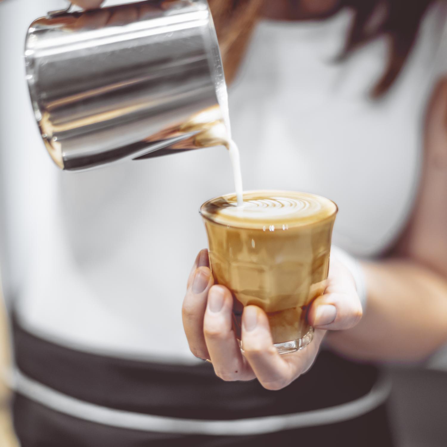 image showing barista pouring coffee into latte glass