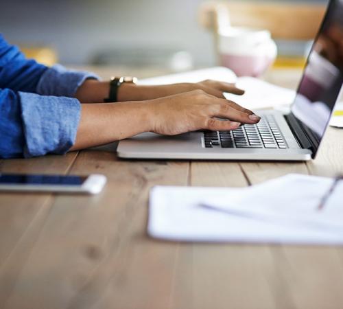 Person conducting business at a desk and typing on a laptop