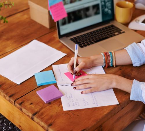 Woman writing notes at a laptop