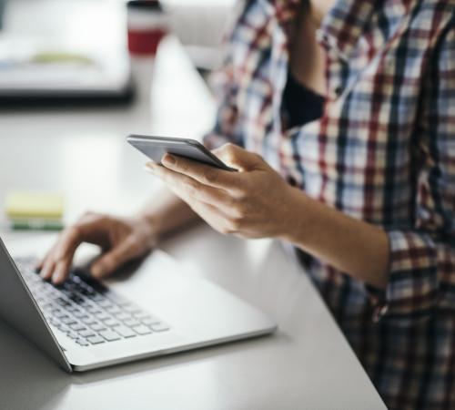 multi-tasking business owner using laptop and phone