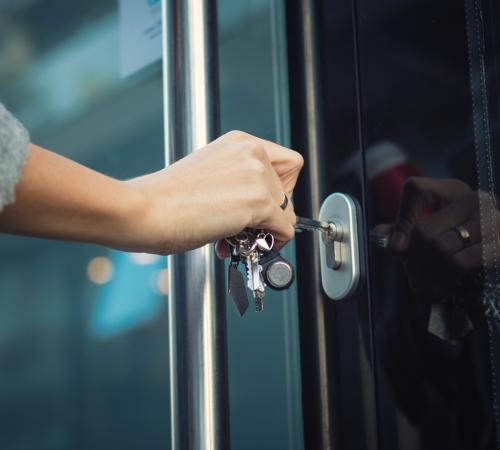 business owner using a key to open front door