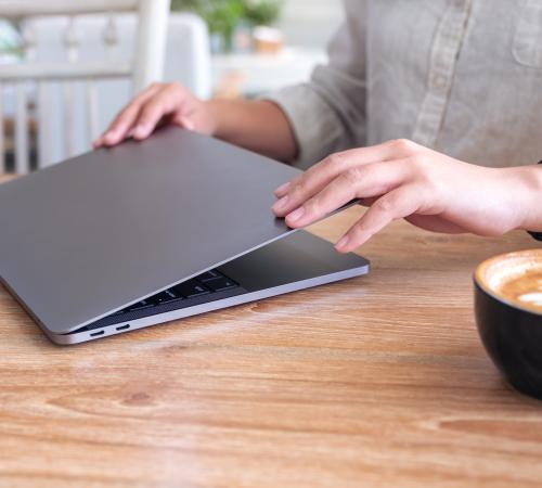 image showing professional opening laptop in cafe with cappuccino on table