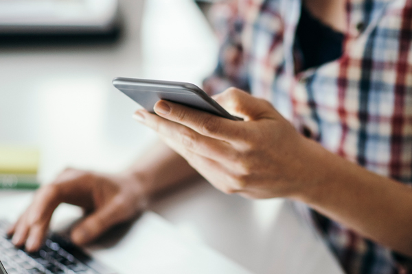 Woman working on phone and laptop