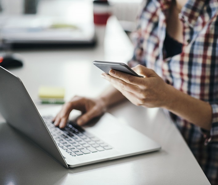 A business owner at her desk, looking at her mobile phone