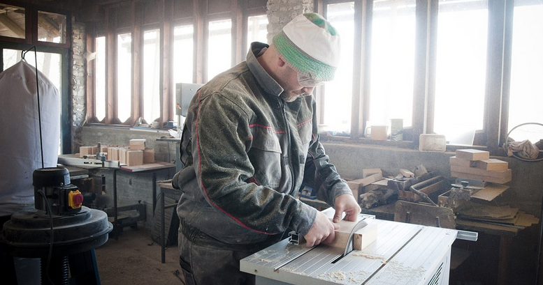 handyman in workshop measuring wearing goggles