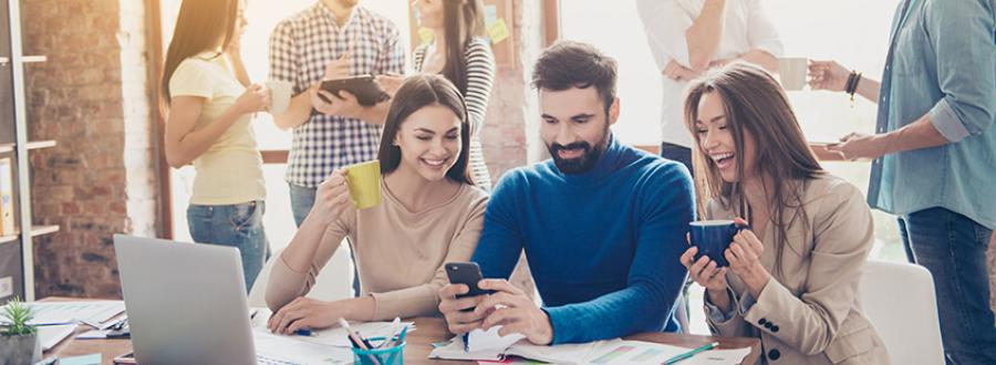 three colleagues enjoying a hot drink and laughing together