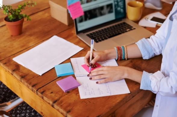 Woman writing notes at a laptop