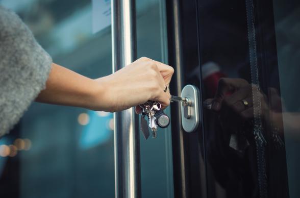 business owner using a key to open front door