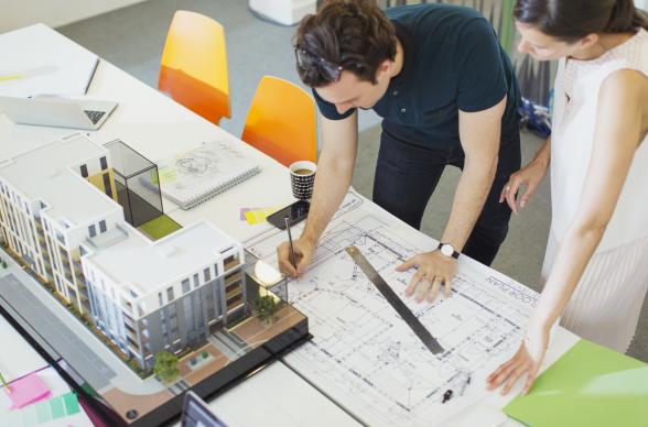 Two architects looking at plans and a model for an office building